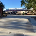 Hardscape construction site with workers and partially built concrete paths, surrounded by buildings and trees.