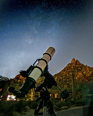 Pinnacle Peak Astronomy Telescope pointed at a starry sky near Pinnacle Peak with illuminated rock formations in the background